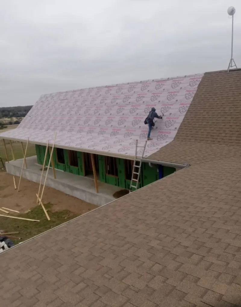 Worker preparing underlayment for a metal roof installation in Ahuimanu
